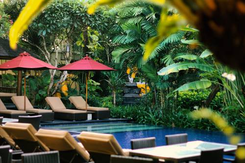 Strafa wypoczynkowa przy basenie wśród dzikiej roślinności w Kamuela Villas and Suites Sanur, Bali, Indonezja