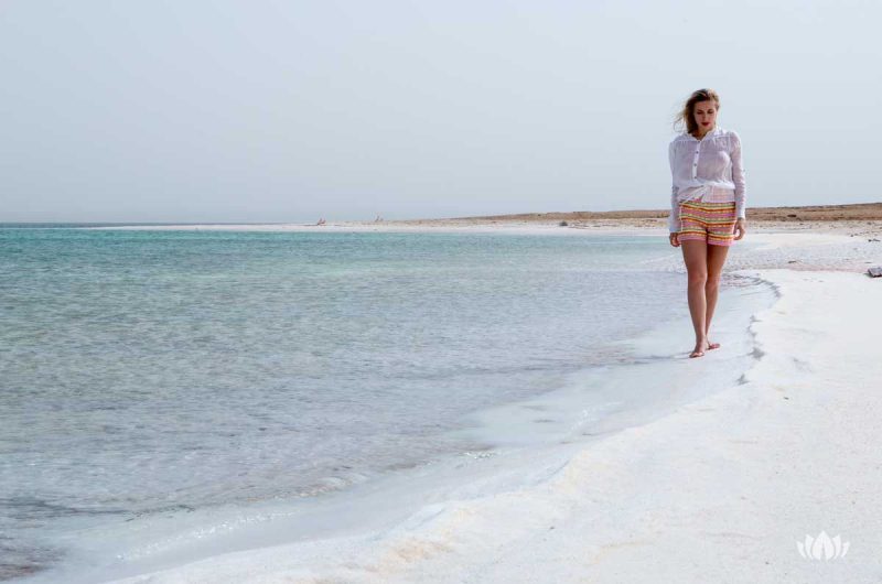 młoda kobieta spacerująca boso brzegiem Morza Martwego w wietrzny dzień
