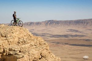 rowerzysta na wzniesieniu podziwiający widoki na pustynii w Izraelu