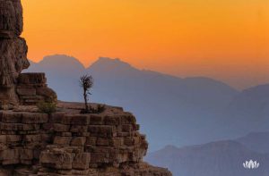 widok ze szczytu na oświetlone zachodzącym słońcem góry w Omanie