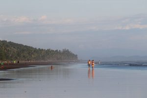 para spacerująca wzdłuż szerokiej plaży brzegiem morza, Kostaryka