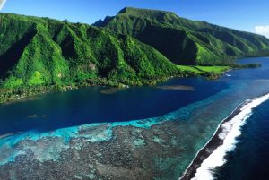 widok z lotu ptaka na kolorową rafę i zieloną wyspę o bujnej roślinności, Polinezja