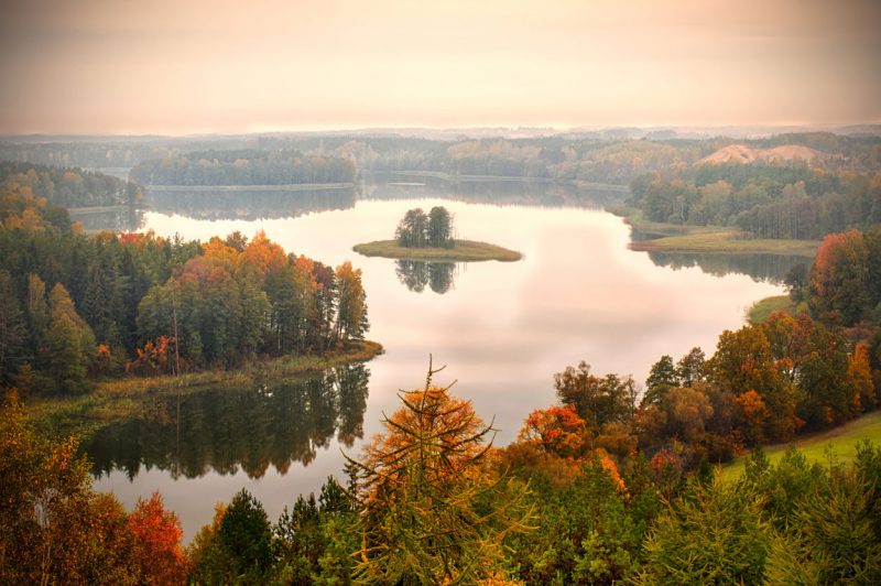 jesienny widok z lotu ptaka na jezioro mazurskie otoczone barwnymi lasami